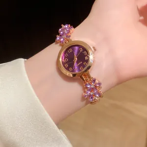 Montre à quartz élégante dorée avec cadran violet et bracelet floral en strass.