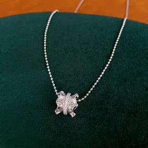 Détail d'un collier argenté avec pendentif plissé serti de zircons étincelants et raffinés.