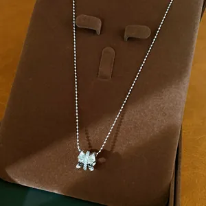 Détail macro d'un pendentif de collier plissé argenté serti de pierres en zircone cubique.