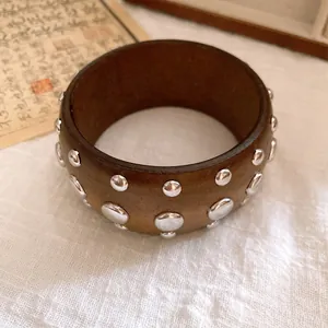 Nahaufnahme eines Vintage-Holzarmreifens mit mehrlagigen silbernen Metallnieten.