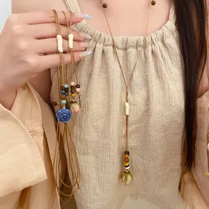 Handmade leather cord necklace with wood beads and resin eternal flower pendant detail.