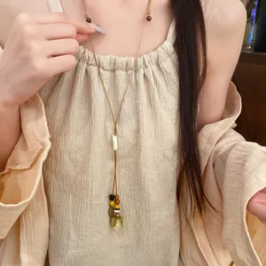 Close-up detail of forest-style long necklace with dried flower pendant and wooden beads