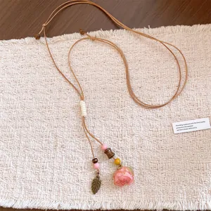 Detailed view of preserved rose flower necklace with wood beads and leaf pendant