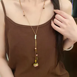 Close-up of handmade leather cord necklace with ceramic flower and leaf pendants