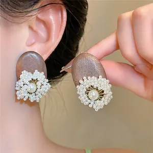 Close-up of ethnic wood earrings with pearl flower design and white glass beads