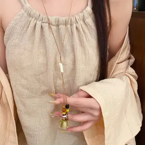 Close-up of preserved flower pendant necklace with leather cord and wooden beads