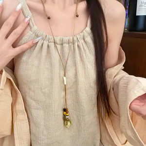 Close-up of a bohemian long pendant necklace featuring preserved flower and wooden beads