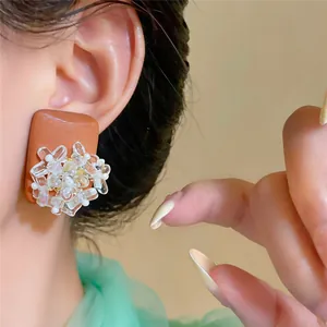 Close-up detail of ethnic style wood earrings with glass flower and pearl accent