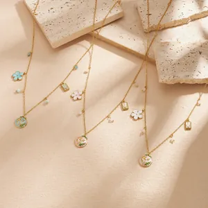 Close-up of gold-plated stainless steel necklaces with enamel floral pendants and beads.