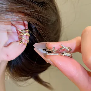 Detalle de ear cuffs de circón en oro y plata con patrón de estrellas puesto en la oreja