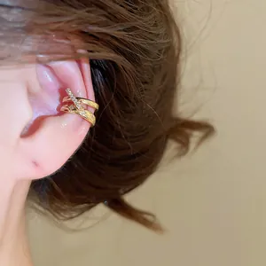 Primer plano de un ear cuff de doble capa dorado con circones y estrellas