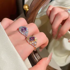 Detalle macro de anillos abiertos de circón morado ovalado bañados en oro de 18k