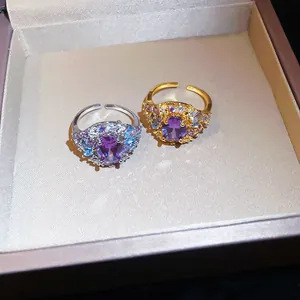 Primer plano de anillos ajustables bañados en oro y plata con piedras de circón púrpura.