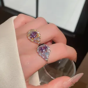 Primer plano de anillos elegantes con piedras óvalos púrpuras y circonitas en mano