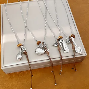 Detail shot of necklaces with silver comb, spoon, and fish pendants on leather cords.