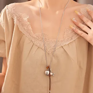 Detailed view of long sweater necklace featuring silver fish and spoon charms on leather cord