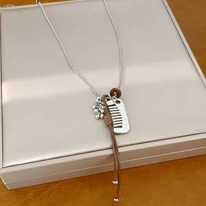 Macro detail of a silver comb pendant charm and brown leather cord on a necklace chain