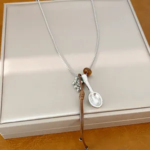 Detail view of silver spoon pendant necklace with leather cord and bead accents.
