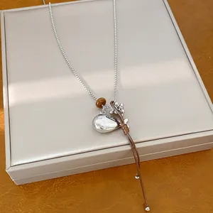 Detail view of stylish fish pendant necklace with silver chain and brown leather cord.
