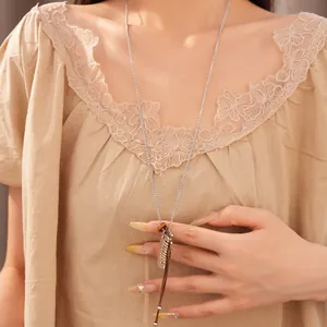Detail shot of a long necklace featuring a small silver comb pendant and resin bead.