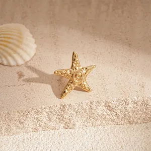 Clip d'oreille étoile de mer doré élégant présenté sur une pierre de sable texturée