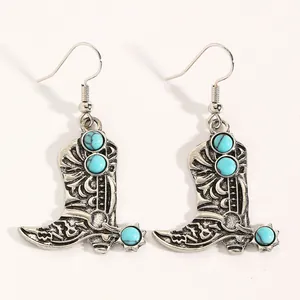 Close-up of vintage silver cowboy boot earrings with inlaid turquoise beads