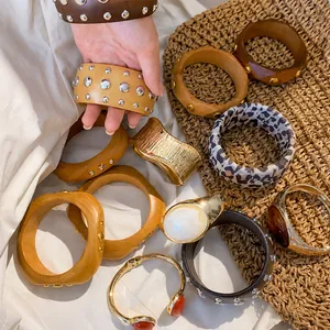 Assorted set of geometric wooden rivet bracelets and metal bangles on a woven mat