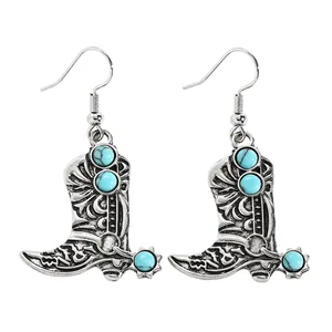 Detailed shot of vintage silver cowboy boot earrings featuring turquoise stone accents.