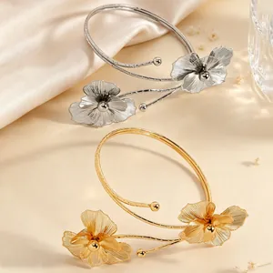 Elegant hollow metal flower arm cuff with intricate petal details in gold and silver.
