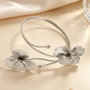 Detailed view of silver hollowed-out metal flower arm cuff with textured petals.