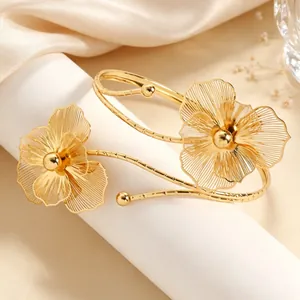 Close-up of elegant gold hollow flower arm cuff with intricate petal details for women