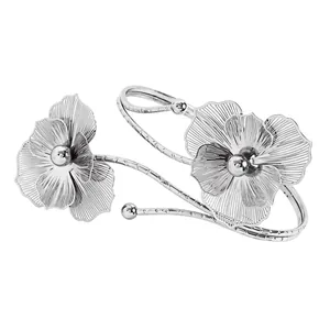 Detailed view of silver-toned metal arm cuff featuring ornate hollow flower designs
