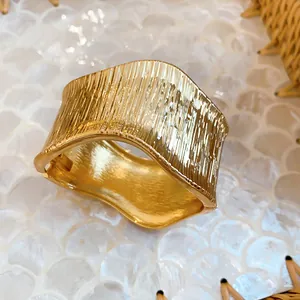 Close-up detail of a textured irregular geometric gold cuff bracelet with ribbed finish