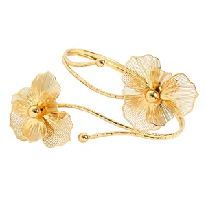 Macro view of gold hollow flower arm cuff showing intricate filigree metal petals