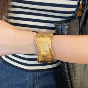 Macro detail of high-quality gold irregular wave textured cuff bracelet on wrist