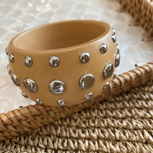 Macro view of a natural wooden bangle decorated with polished silver metal rivets