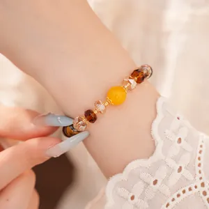 Primer plano detallado de una pulsera vintage de cuentas de ojo de tigre con toques amarillos.
