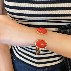 Close-up of irregular geometric gold cuff bracelet with large oval red stones.