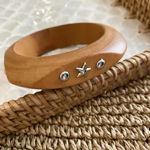 Detailed close-up of a rustic wooden bangle with star and rivet metal accents
