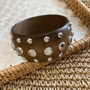 Close-up detail of a dark wood bangle with polished silver metal stud accents