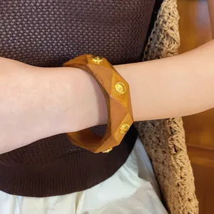Detailed macro view of an irregular geometric wooden bangle with gold-tone metal studs