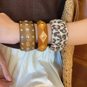 Detail showing a stack of three chunky fashion bangles with rivets and leopard print