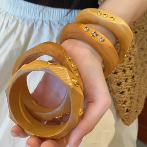 Detailed view of irregular geometric wooden bracelets with metallic stud accents.
