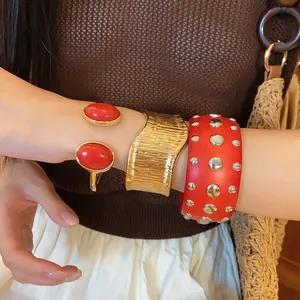 Detailed view of fashionable red wood rivet bracelet and gold geometric cuffs on a wrist