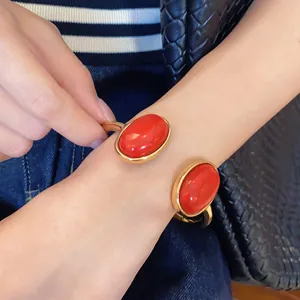 Detailed close-up of an elegant gold open cuff bracelet with two large oval red stones