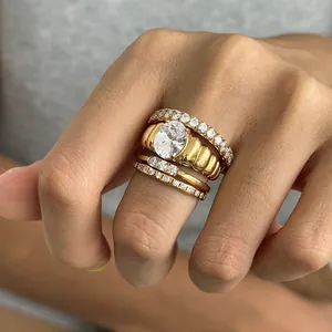 Primer plano de anillos apilados de acero inoxidable dorado con piedra ovalada