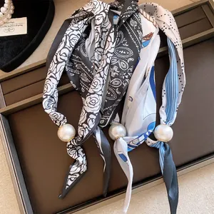 Gros plan de colliers en foulard de soie élégants avec de grands pendentifs en perles blanches.