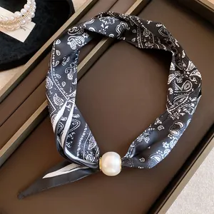 Gros plan d'un collier en foulard de soie paisley noir avec fermoir magnétique en perle