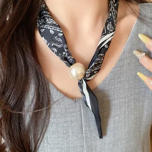 Gros plan d'un collier en soie élégant avec imprimé bandana et grosse perle