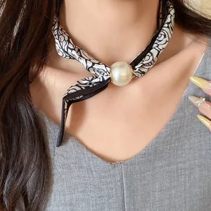 Gros plan d'un collier foulard en soie style français avec perle élégante sur le cou